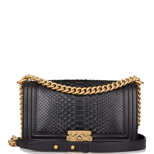 Black textured handbag with gold chain and clasp on a white background